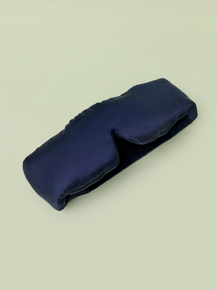 Lunya Silk Sleep mask resting against light green background.
