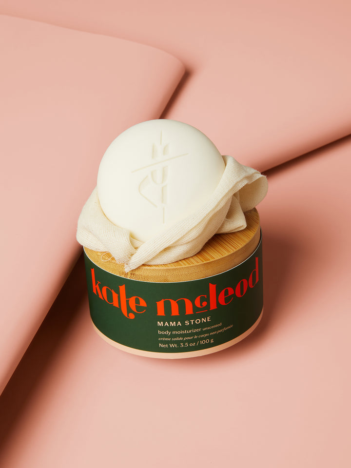 The Mama Stone packaged with a wooden lid on a pink background