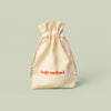 Beige drawstring canvas bag, the Mini Gift Bag, with 'Kate McLeod' logo on a light green background.
