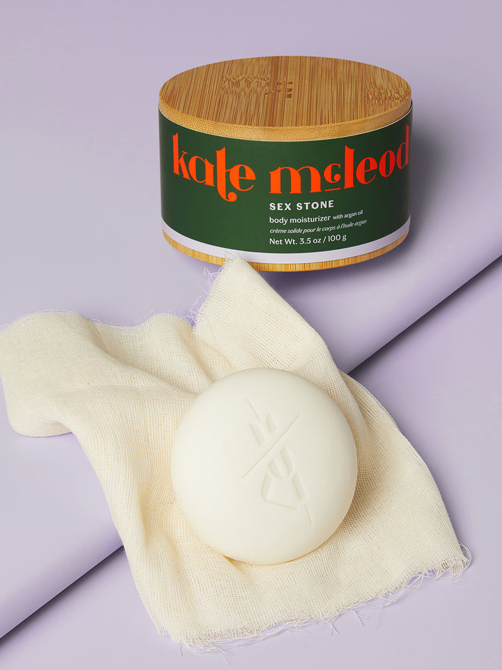 Kate McLeod Sex Stone with a bamboo canister and muslin cloth against a light purple background