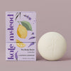 Lavender Lemonade body stone lotion bar with citrus packaging on a light lavender background.
