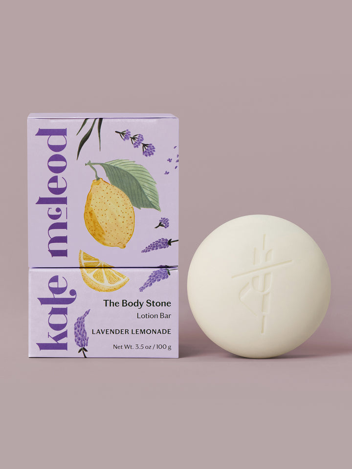 Lavender Lemonade body stone lotion bar with citrus packaging on a light lavender background.