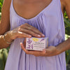 Person in a light purple dress holding the lavender lemonade body stone in a beautiful box against a natural background