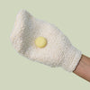 A hand wearing the Body Mitt with a Pebble on it against a ight green background.