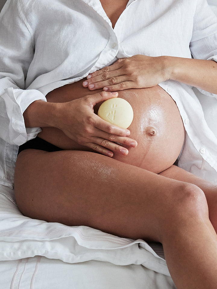 Pregnant woman holding the Mama Stone against their belly