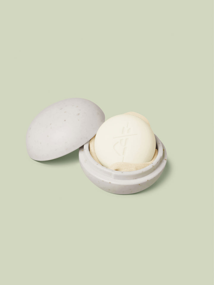 Mini Travel Case in ivory oatmeal color laying open with a mini Body Stone nestled inside on a light green background.