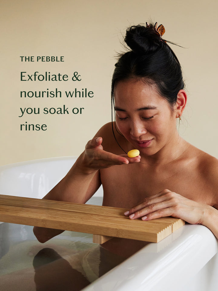 Woman in a bathtub holding a Pebble with text about exfoliating and nourishing.