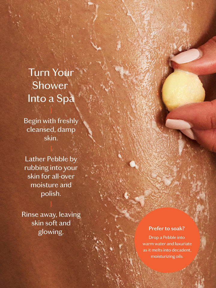 Person applying a lathered Pebble to their skin with text on how to use it. Turn your shower into a spa.