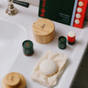 The Bamboo Canister styled on the surface of a bath alongside Kate McLeod's Body Brush, The Face Balm, The Everywhere Stick and Sleep Pebble