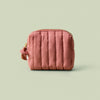 Blush quilted mini travel bag on a light green background