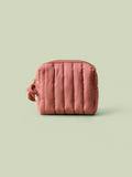 Blush quilted mini travel bag on a light green background