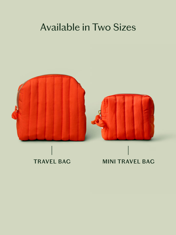 The Travel Bag, a poppy-orange quilted, zippered pouch, against a light green background. Shows the 2 different sizes offered: original travel sized bag and mini travel bag.