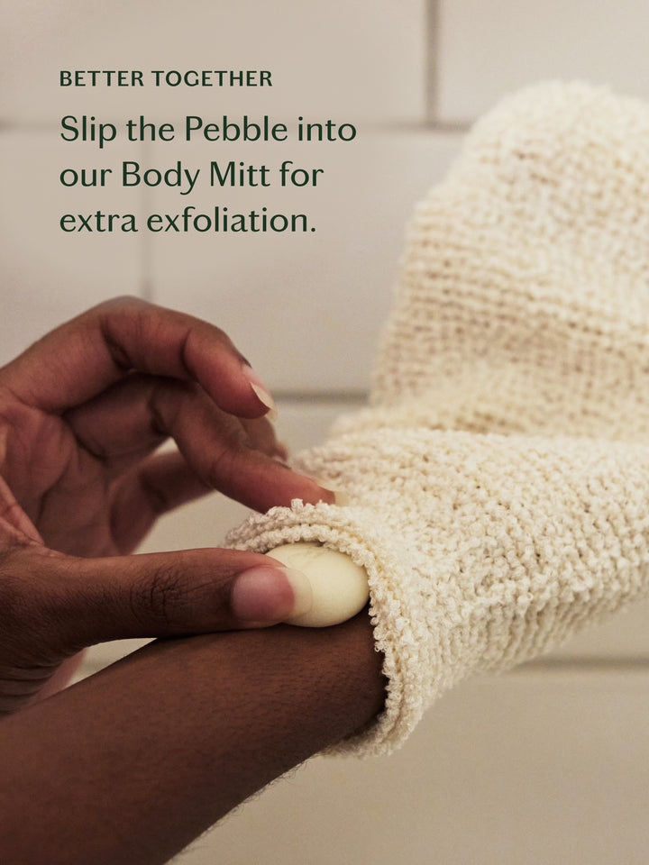 Person using a bamboo Body Mitt with a Pebble for exfoliation, text overlay 'Better Together'. Slip the Pebble into our Body Mitt for extra exfoliation.