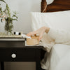 Woman reaching for body stone bamboo canister on bed-side table