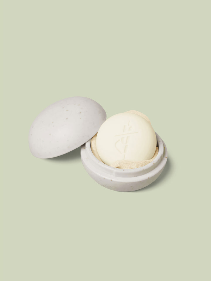 Mini Travel Case in ivory color laying open with a mini Body Stone nestled inside on a light green background.