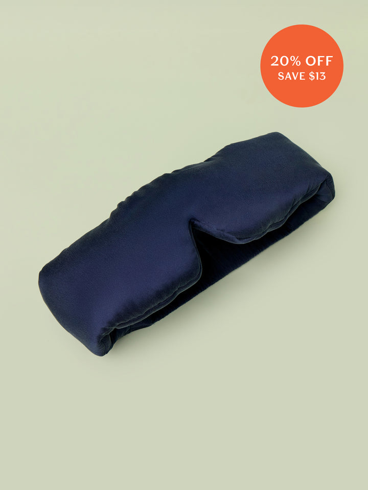 Lunya Silk Sleep mask resting against light green background.