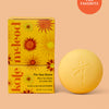 Yellow after sun balm bar and packaging on a peach background