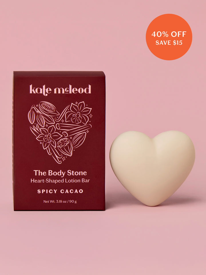 Heart-shaped lotion bar with packaging on a pink background