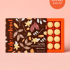 Box of Kate McLeod Amber & Vanilla solid bath and shower oil with brown floral illustrated packaging design on a light pink background.