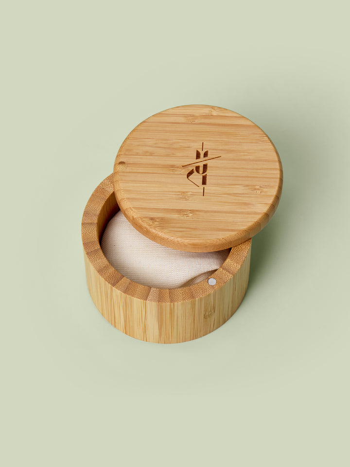 Bamboo Canister with lid that swings open pictured against green background with a Body Stone lotion bar nestled inside. Body Sones sold separately.