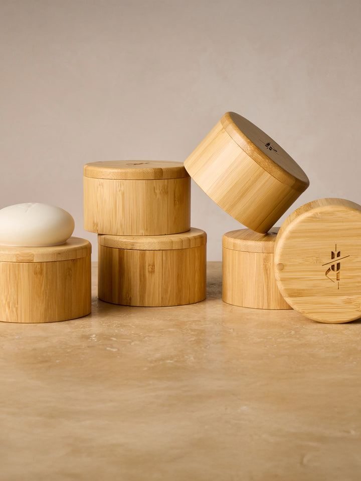 Stack of bamboo containers on a wooden surface with a neutral background