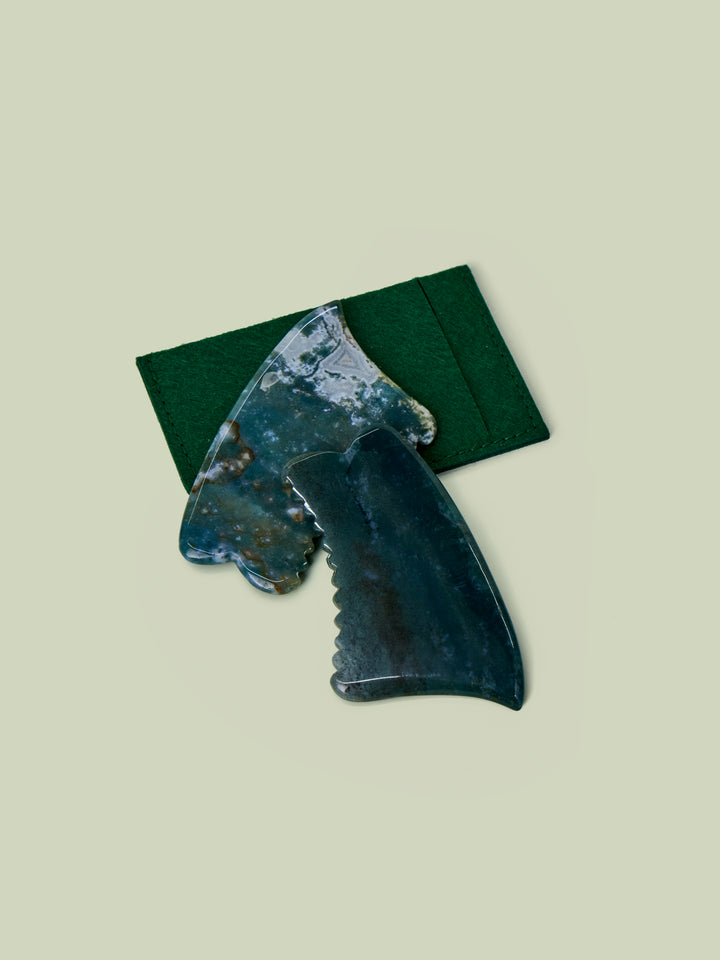 Two Face Gua Shas with green felt case overlaid on light green background.