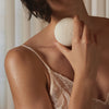 Person holding a white Sex Stone near their neck against a neutral background