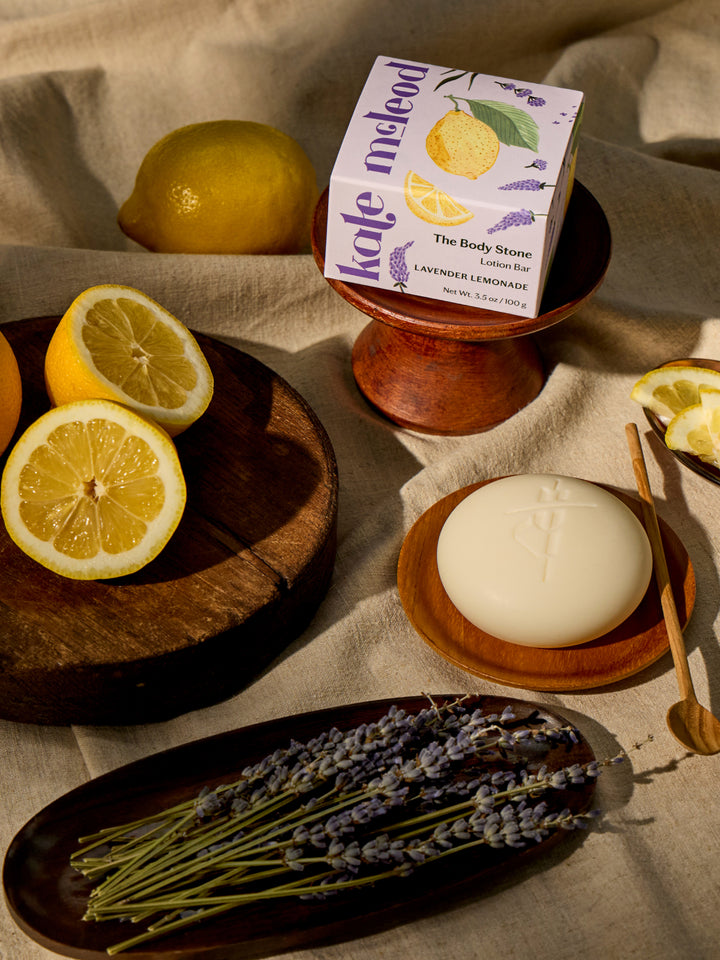 The New Summer Limited-Edition Lavender Lemonade Body Stone box styled next to the body stone, alongside fresh lemons and lavender.