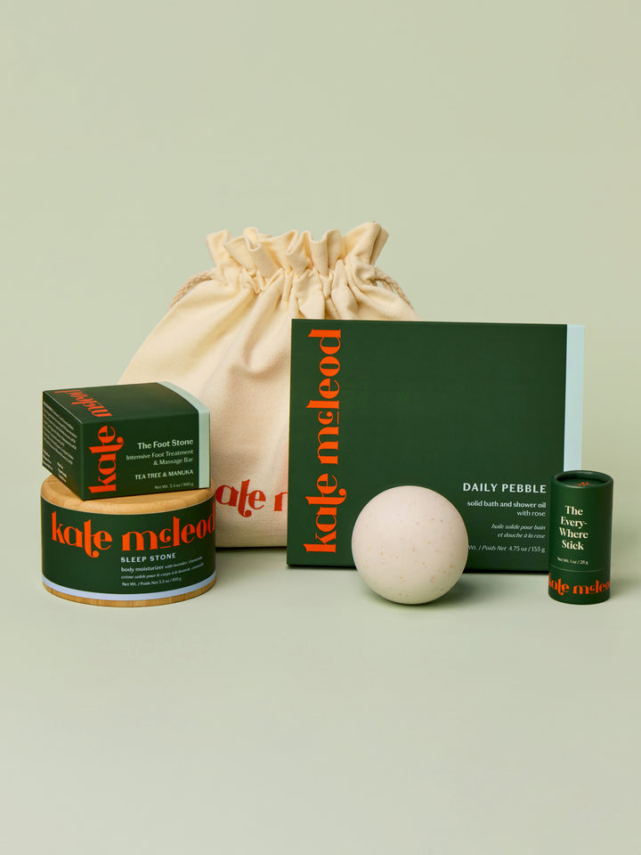 Display of what can fit inside the large gift bag. A Body Stone Refill, a Body Stone Starter Kit, Pebble box, Mini Travel Case, and Everywhere Stick.