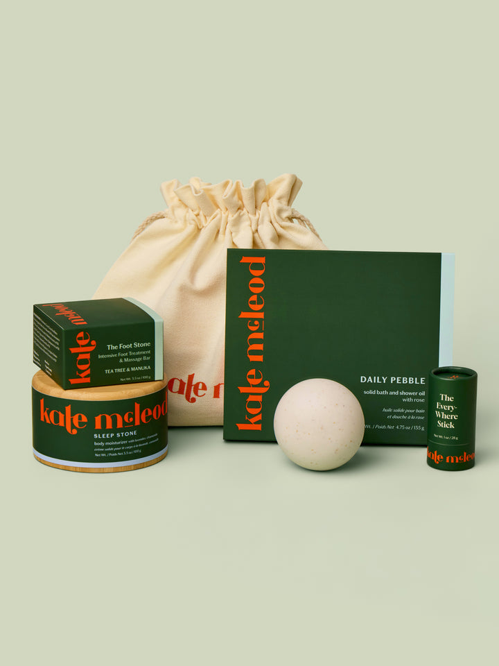 Display of what can fit inside the large gift bag. A Body Stone Refill, a Body Stone Starter Kit, Pebble box, Mini Travel Case, and Everywhere Stick.