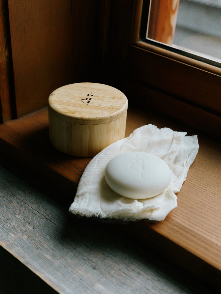 Bamboo container styled beside the best-selling Kate McLeod body stone sitting atop a window seal. 