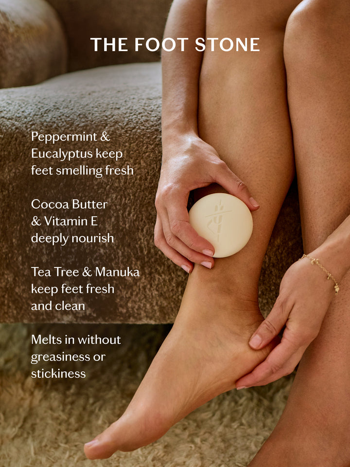 Person applying a foot stone to their leg with product details on a textured surface.