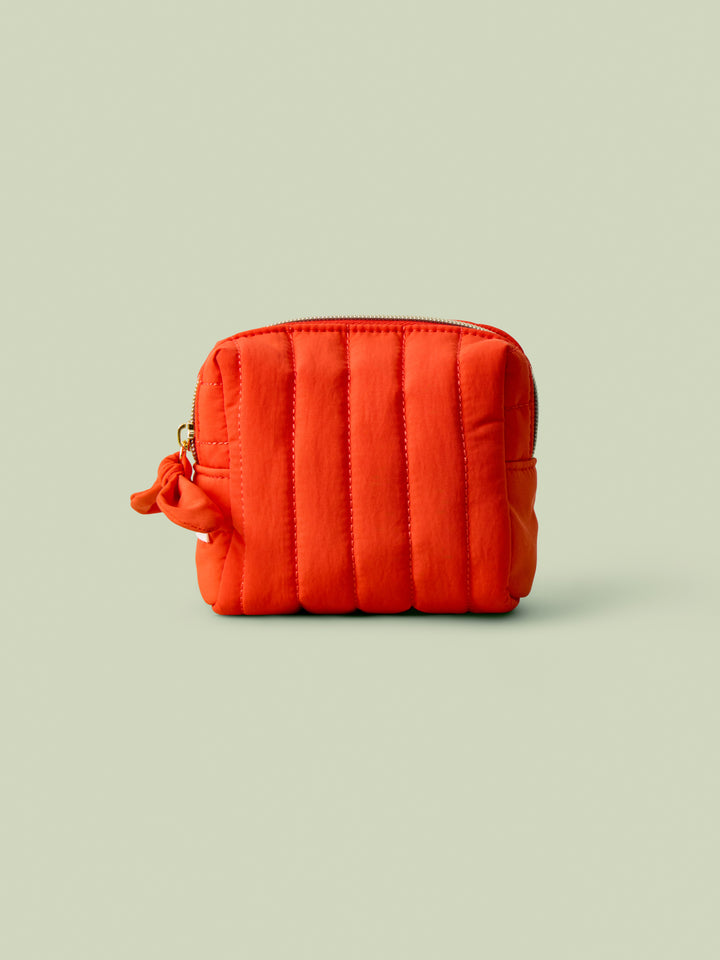 Poppy quilted mini travel bag on a light green background.