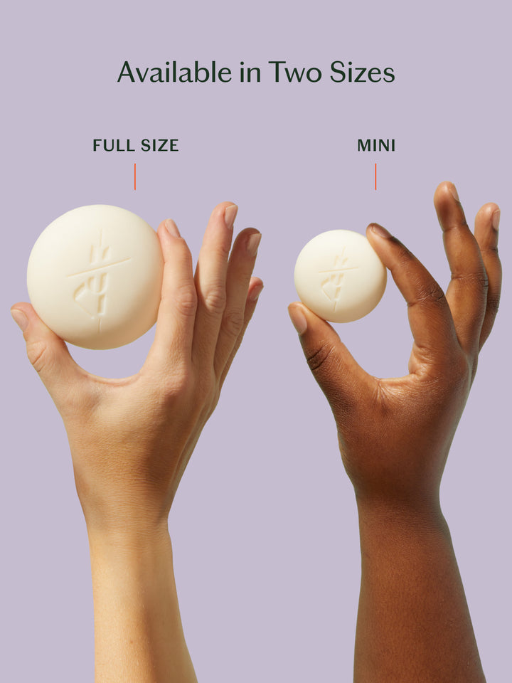 Two hands holding a full-size and a mini-sized product against a light purple background