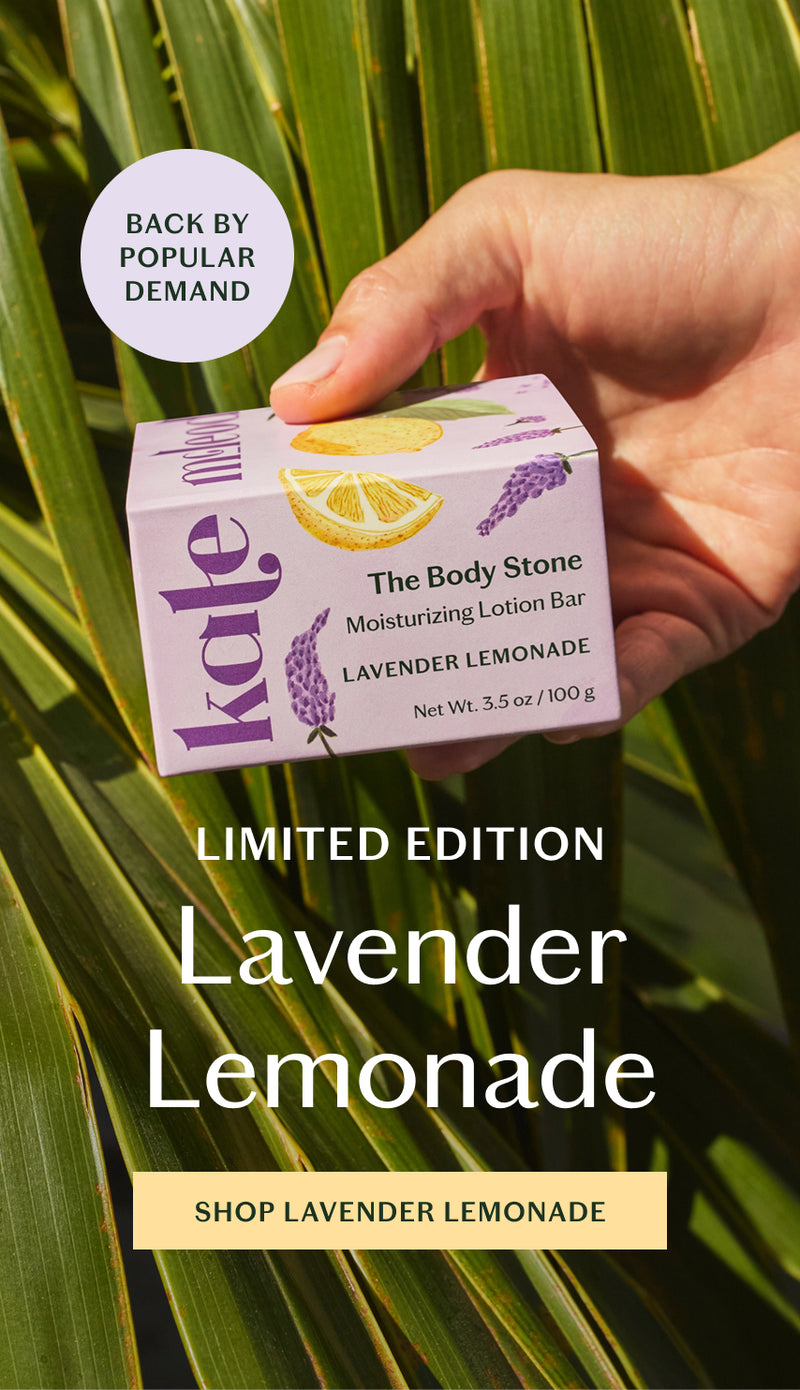 A refreshing take on summer, limited-edition Lavender Lemonade blends herbaceous lavender with bright, zesty lemon. Holding the body stone in its lavender and citrus packaging on a background of palmetto leaves.