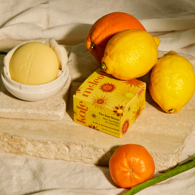The Sun Stone sits atop a decorated table surrounded by citrus fruits on a calming beige background.