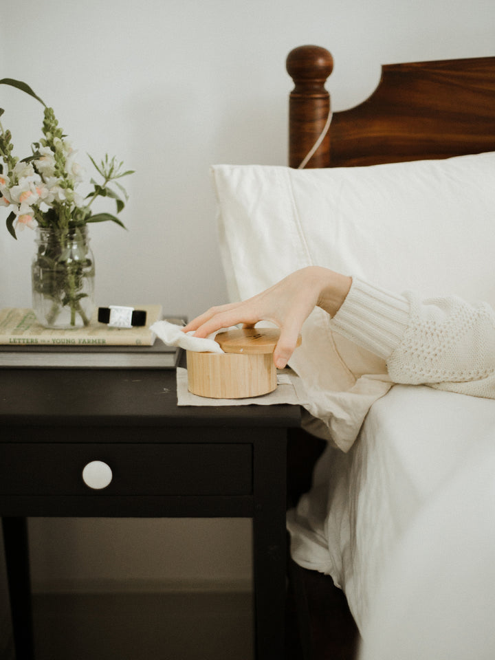 Woman reaching for body stone bamboo canister on bed-side table