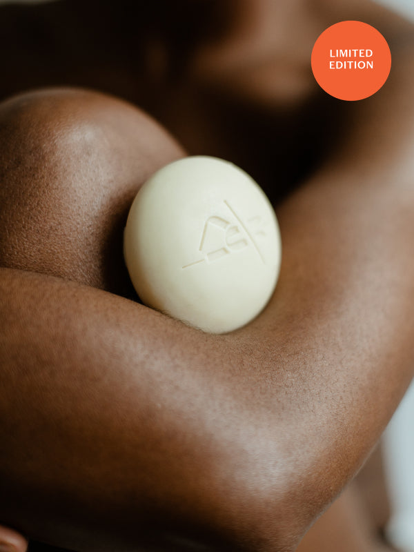 Image of Kate McLeod Body Stone solid moisturizer against nourished, glowing skin.